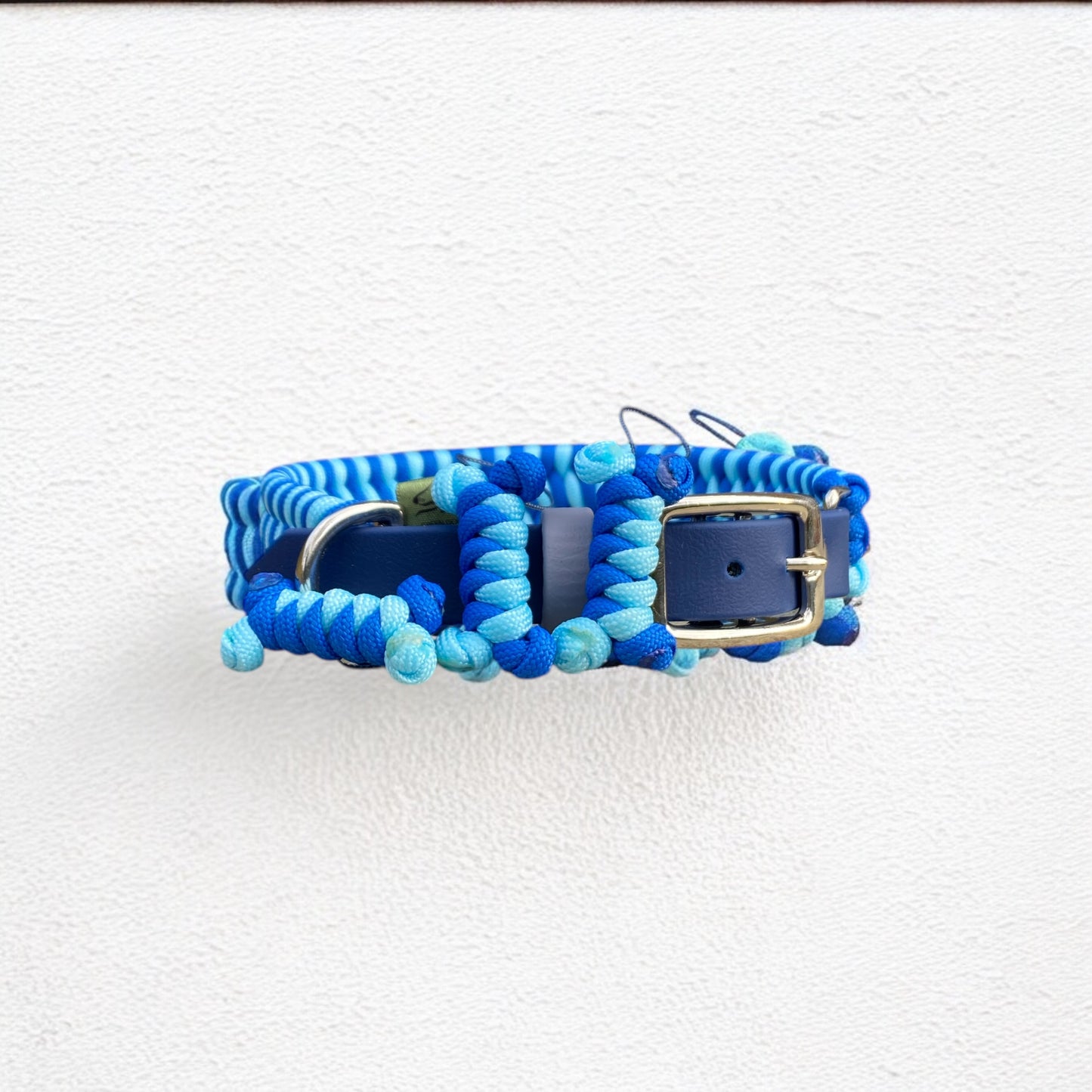 Front view of the Sunny Sky Adjustable Cord Dog Collar, highlighting the Sky Blue and Royal Blue cords, central nickel hardware, and 3 signature bone tassel charms.