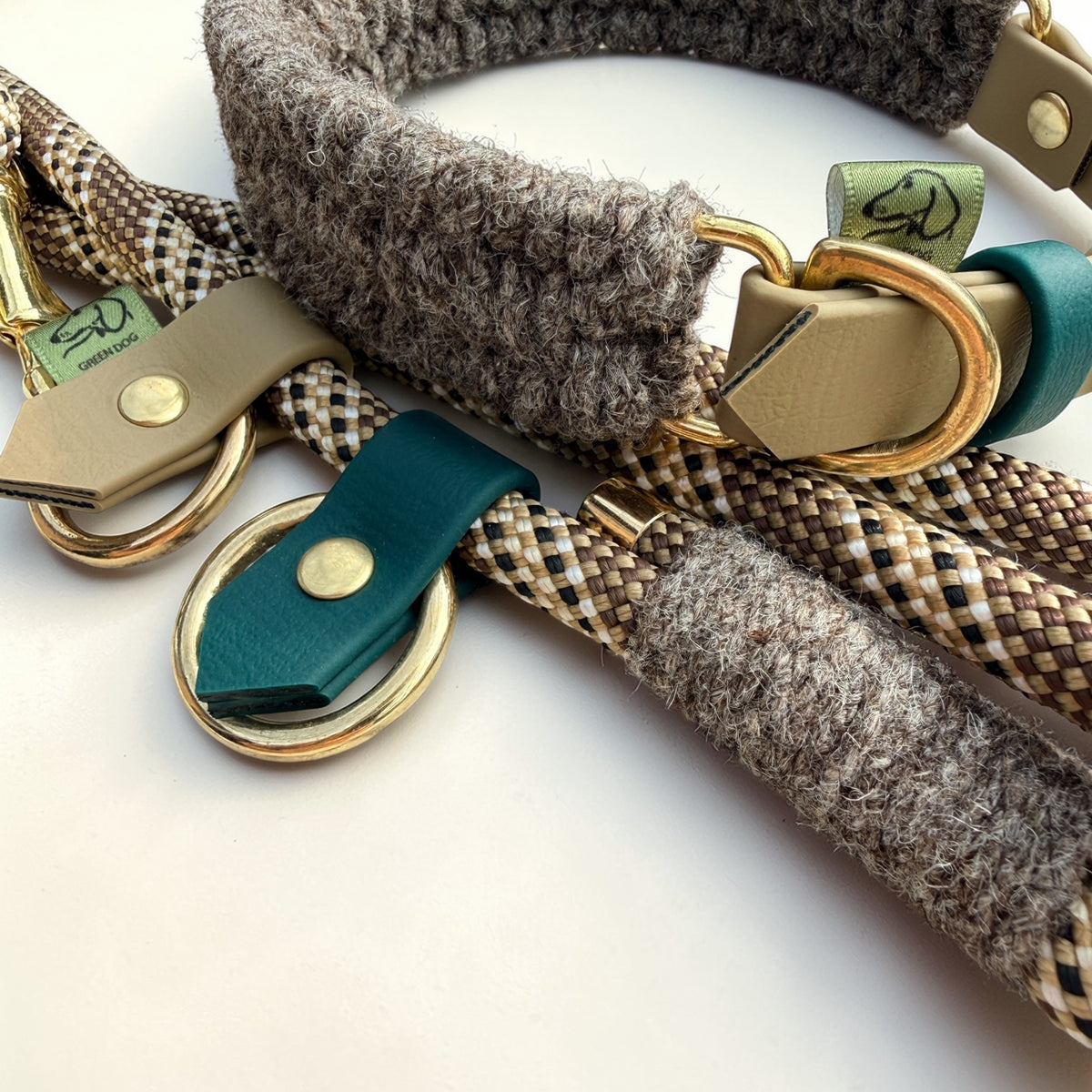 Extreme close-up of Brampton Hybrid rope lead detail — teal BioThane loop tab with solid brass rivet and O-ring, grey Brampton wool binding on chestnut PPM rope, collar beige BioThane strap and brass D-ring visible behind
