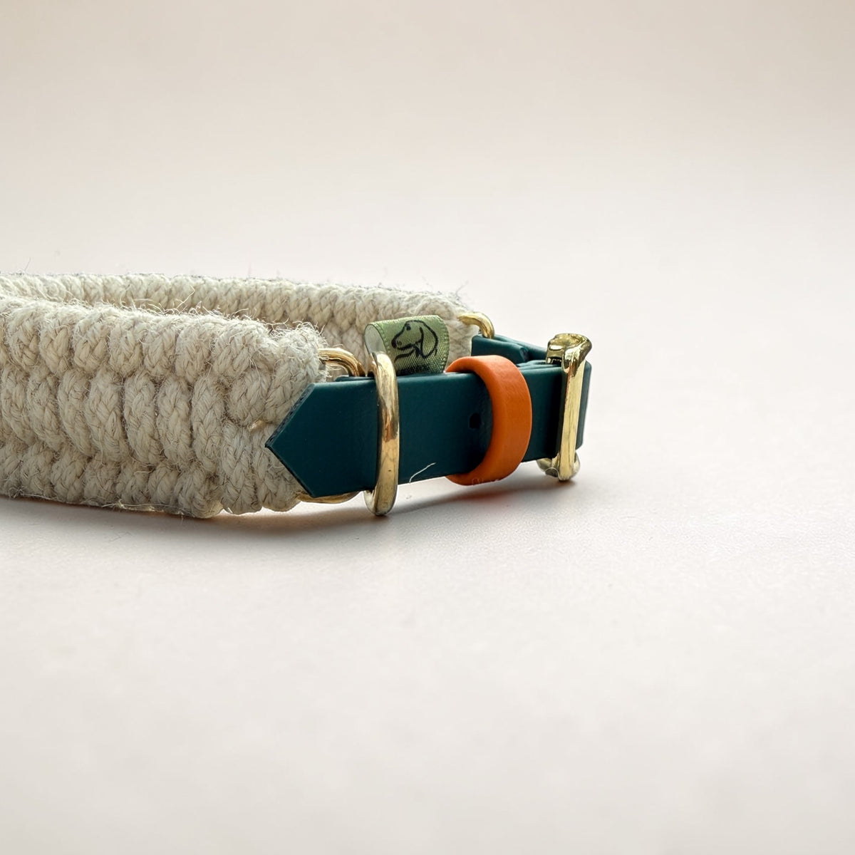 Detailed close-up of Dingley Hybrid collar hardware — hunter green BioThane strap, orange BioThane collar keeper, solid brass D-ring and Green Dog woven label, Sheep Shed Hybrid range