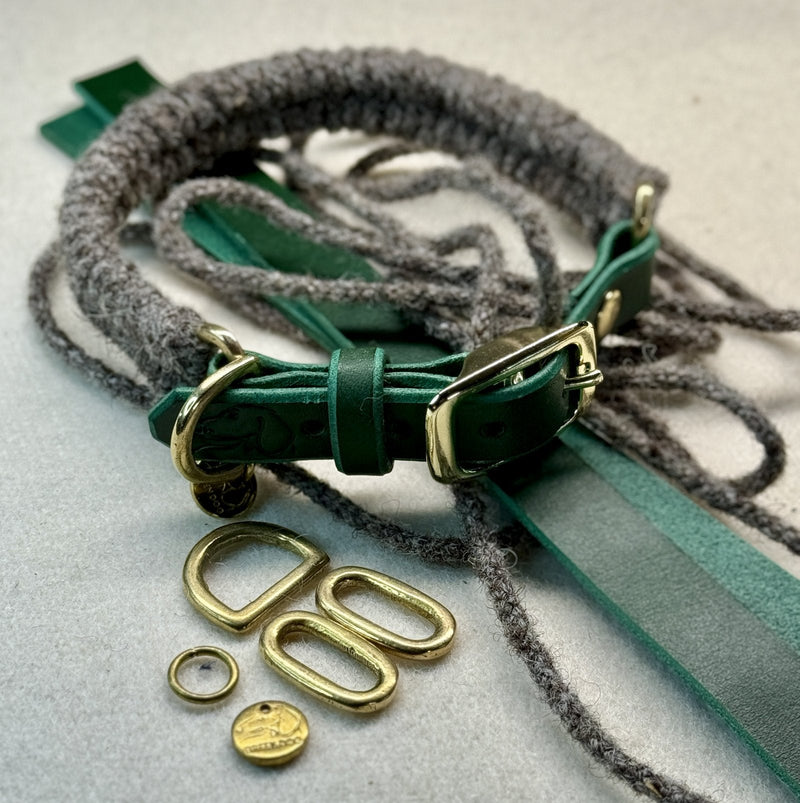 Hunter green leather dog collar with a gold buckle and brass D-ring, shown with a natural grey British wool rope lead and spare brass fittings