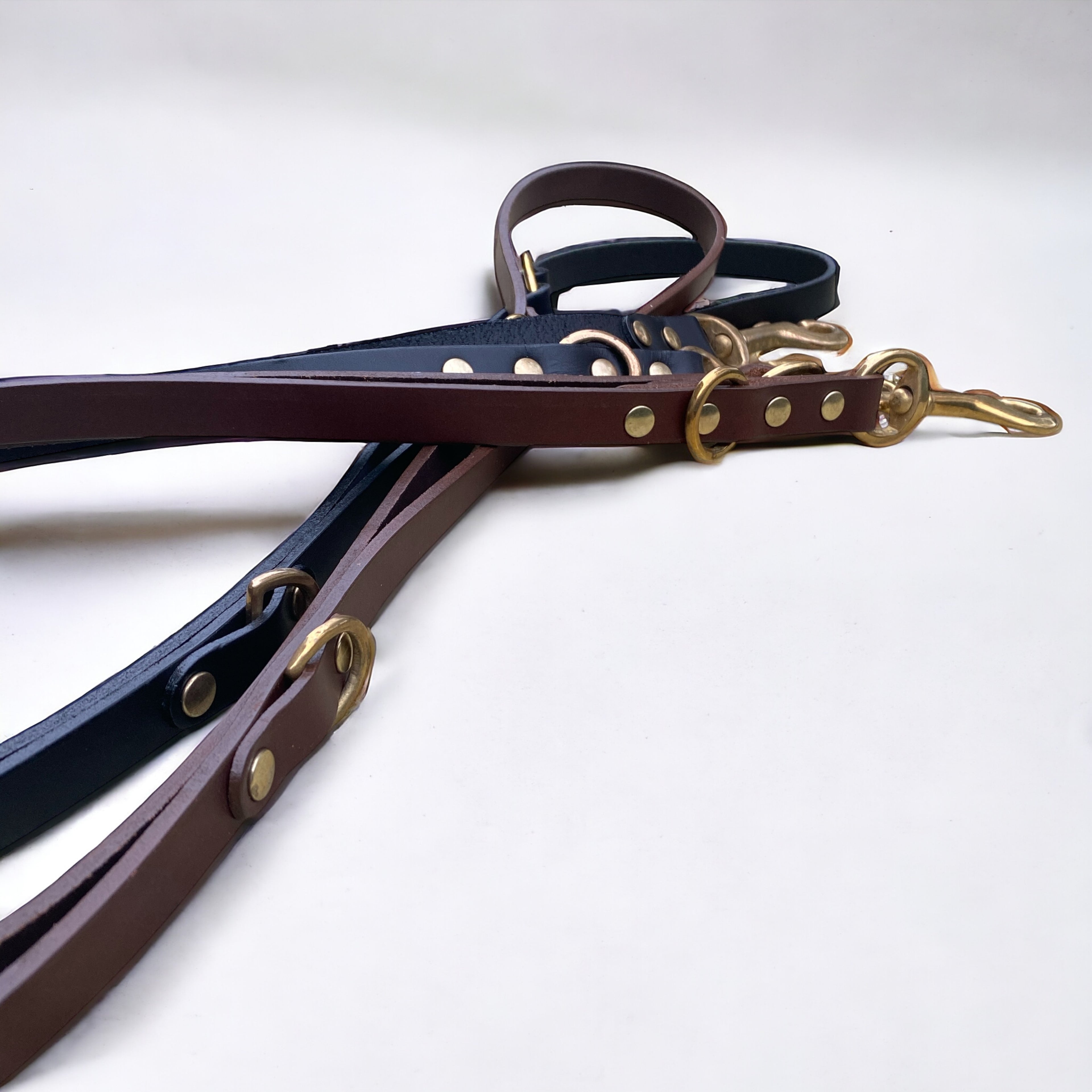 Close-up of handmade luxury leather hands free dog lead in chestnut brown and black cowhide leather with solid brass hardware.