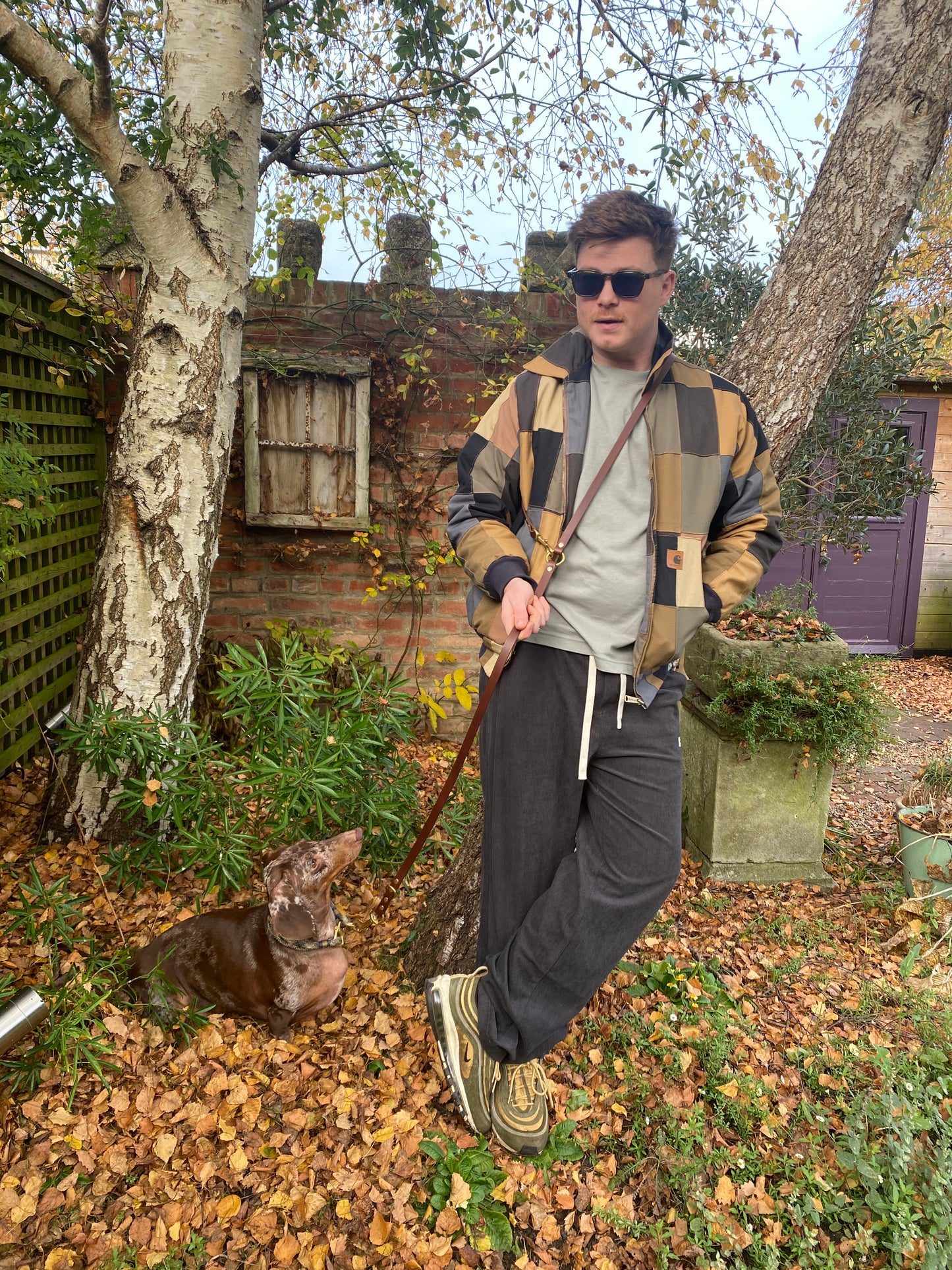 Side-by-side close-up of chestnut brown and black handmade luxury leather hands free dog leads with solid brass hardware.