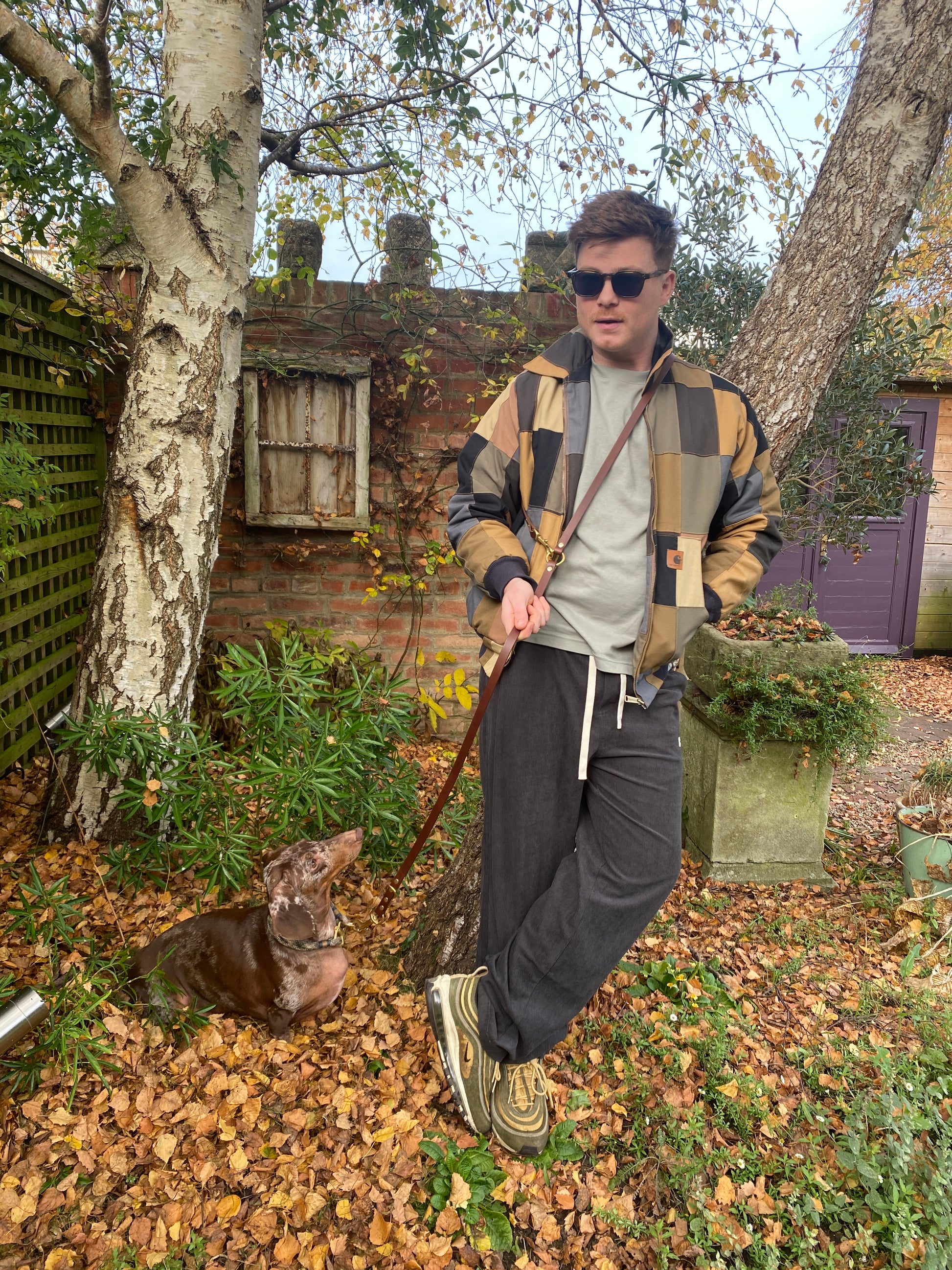 Side-by-side close-up of chestnut brown and black handmade luxury leather hands free dog leads with solid brass hardware.