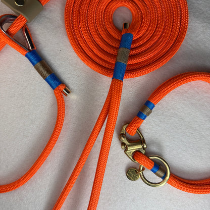 Close up of the neon orange 6mm rope dog lead and mini collar showing classic blue and tan nano binding detail, beige BioThane slider on the lead, and brass shackle with o-ring on the collar.