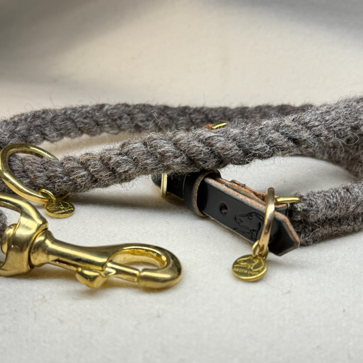 Close up of the brampton wool rope dog lead and dog collar with black bridle leather and brass detail on a light woollen background