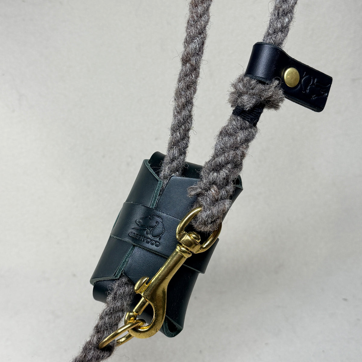 Hunter green leather poo bag holder hand embossed with the Green Dog mark, fastened to a wool rope dog lead with a solid brass trigger clip