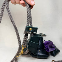 Hunter green leather poo bag holder open to show a roll of poo bags stored inside, with its stud fastened leather tab closure in the Sam Browne style