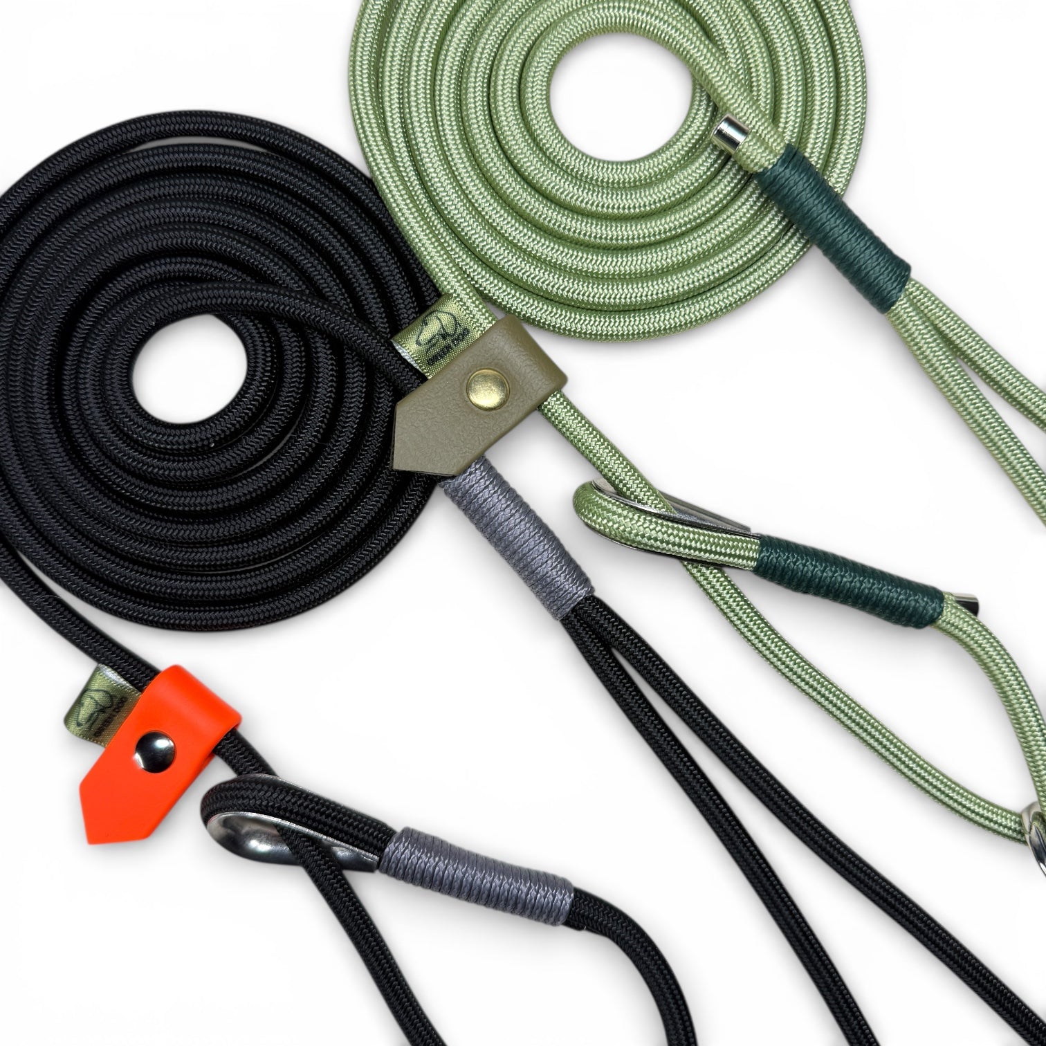 A close up of two custom figure of 8 slip leads n black rope and guac rope colours with charcoal and hunter green bindings, military green and neon orange stoppers designed by customers