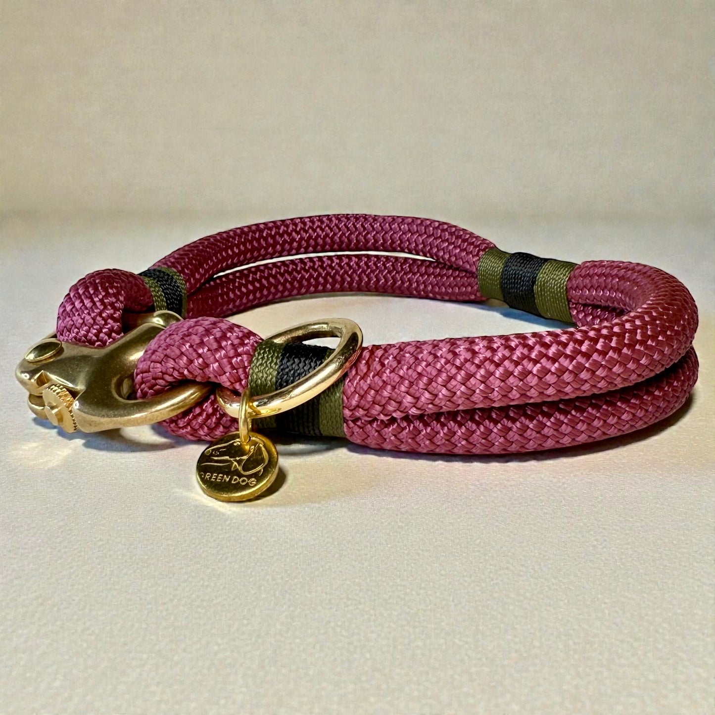 A side on shot of the Greenwich Yarn rope dog collar Bordeaux Edition with maroon rope, olive drab and black binding and brass hardware