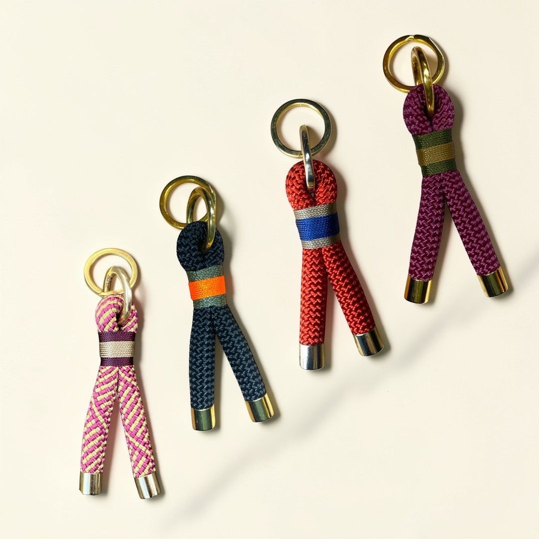 Four handmade Greenwich Yarn keyrings displayed in a diagonal layout, featuring custom rope colour combinations, contrast bindings and polished hardware on a soft neutral background.