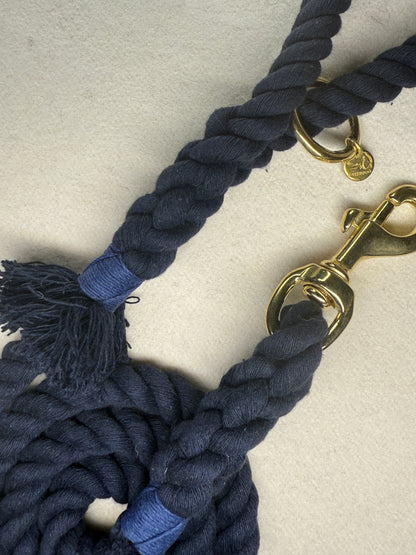 Close up of the midnight blue braided cotton rope dog lead with brass clasp, navy blue binding on a light woollen background