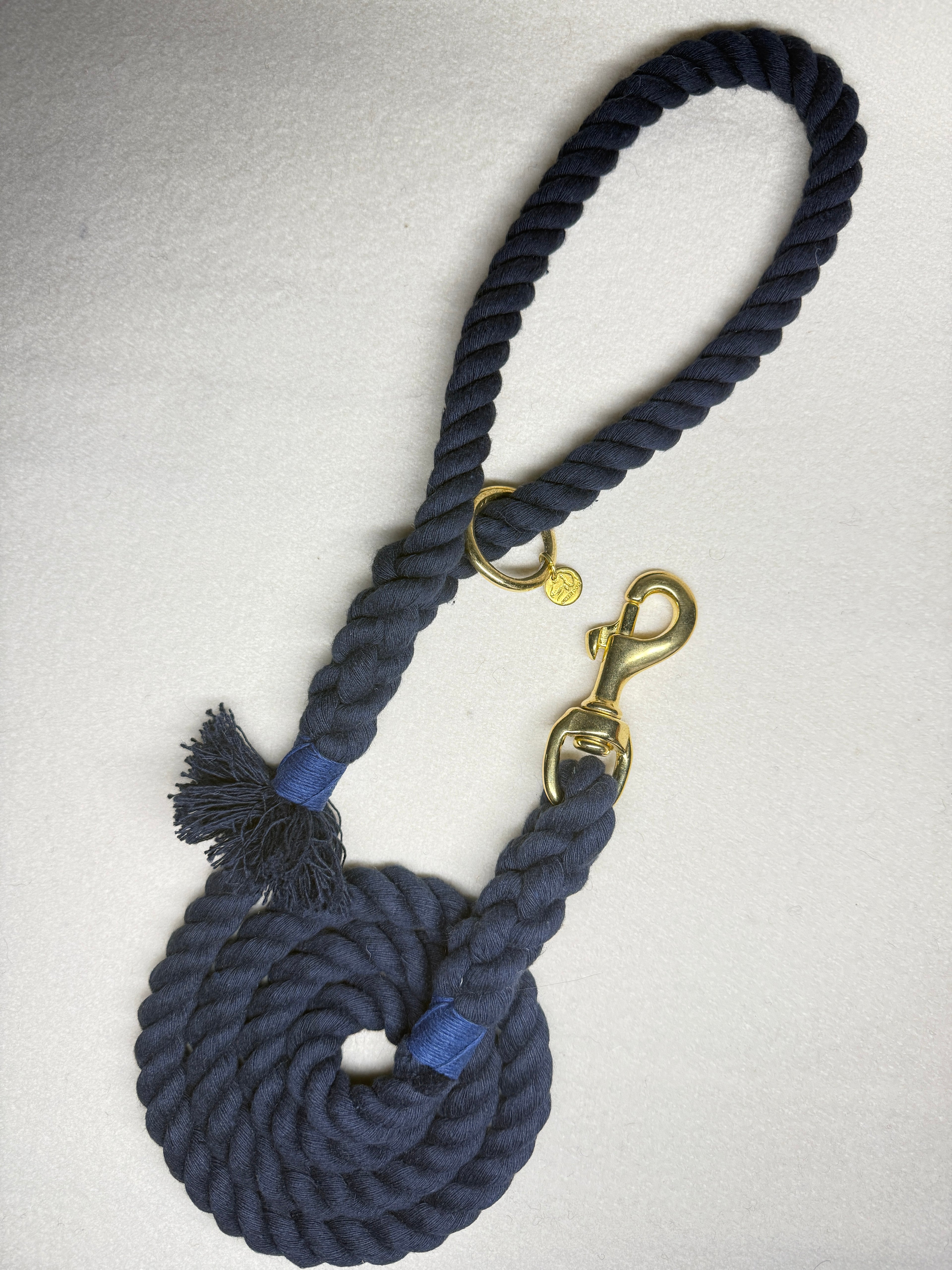 Midnight blue braided cotton rope dog lead with brass clasp, navy blue binding on a light woollen background