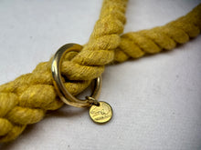 Mustard Yellow Cotton braided rope dog lead close up with brass hardware on a light woollen background