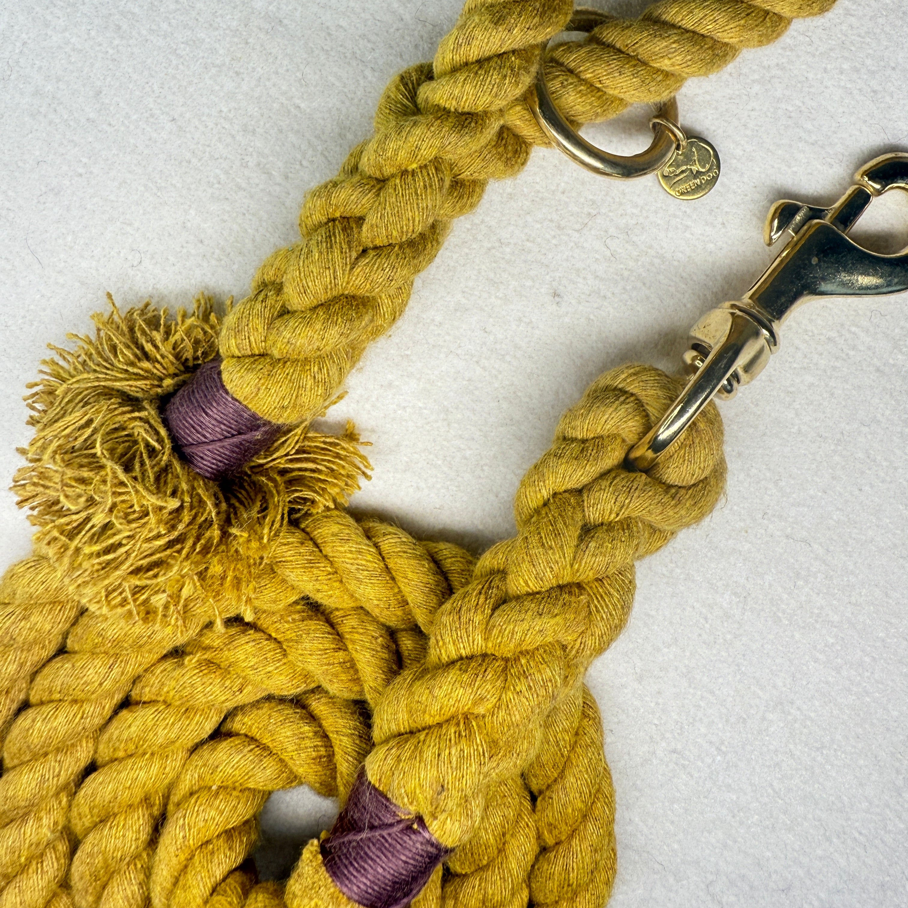 Mustard Yellow Cotton braided rope dog lead close up with brass hardware and brown binding on a light woollen background
