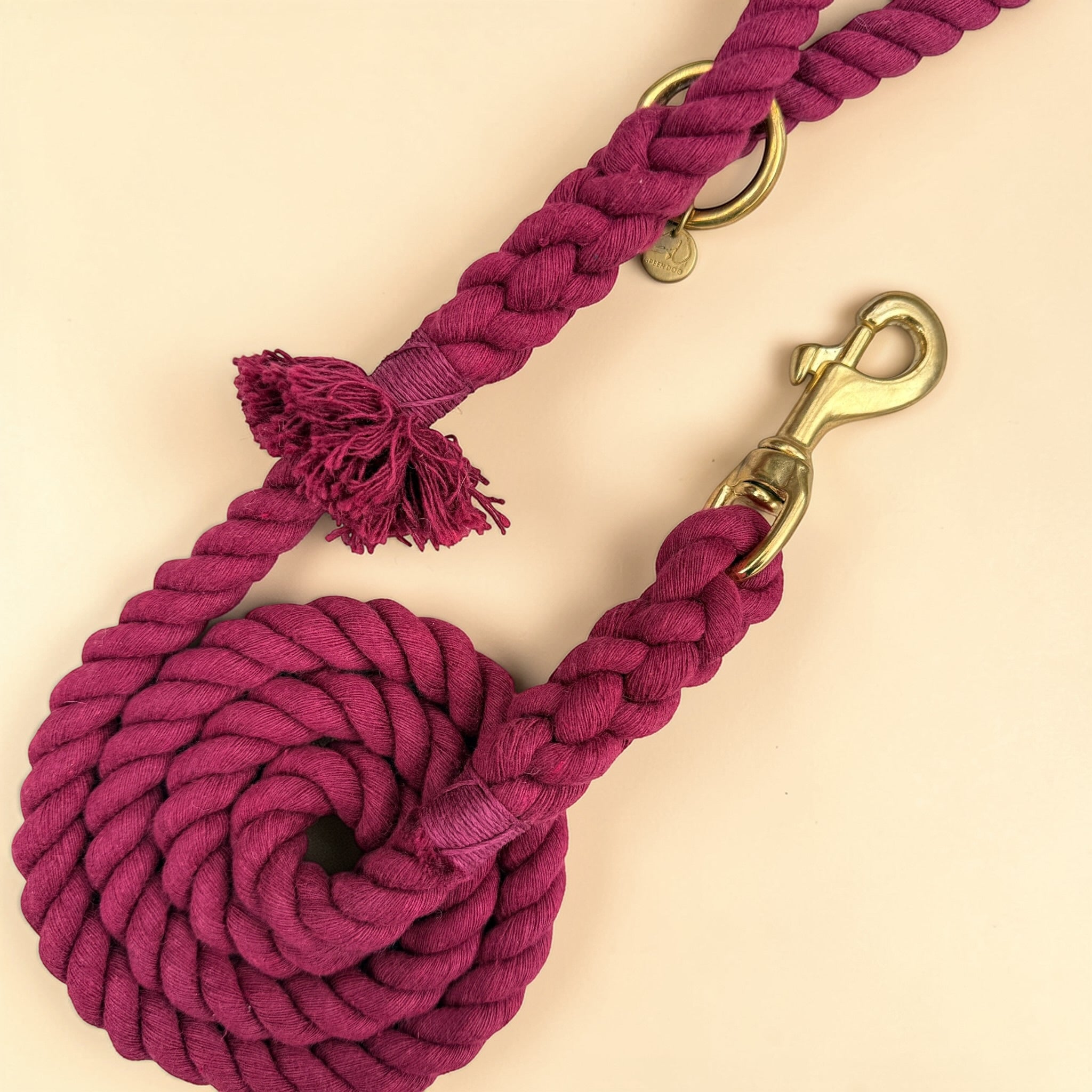 Close-up of burgundy cotton rope dog lead showing the frayed tassel at the handle, matching burgundy binding, solid brass O-ring and trigger snap clip