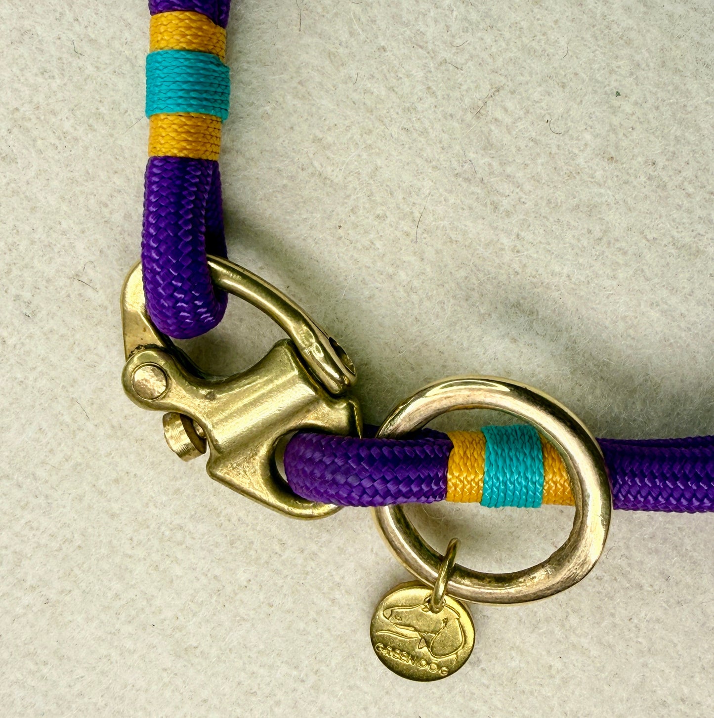 Close-up of solid brass Swedish sailing shackle on a 6mm small dog rope collar, with airforce gold and teal nano binding and brass O-ring