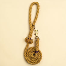 Harvest yellow handmade cotton rope dog lead coiled flat lay, with brass snap clip, brass O-ring, green dog charm tag and purple binding detail