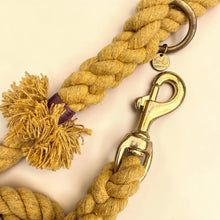Detailed close-up of solid brass trigger snap clip and O-ring on harvest yellow handmade cotton rope dog lead, with Green Dog branded charm tag and tassel detail