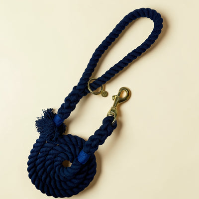 Midnight blue handmade cotton rope dog lead coiled flat lay, with solid brass snap clip, brass O-ring, Green Dog charm tag and cobalt blue binding detail