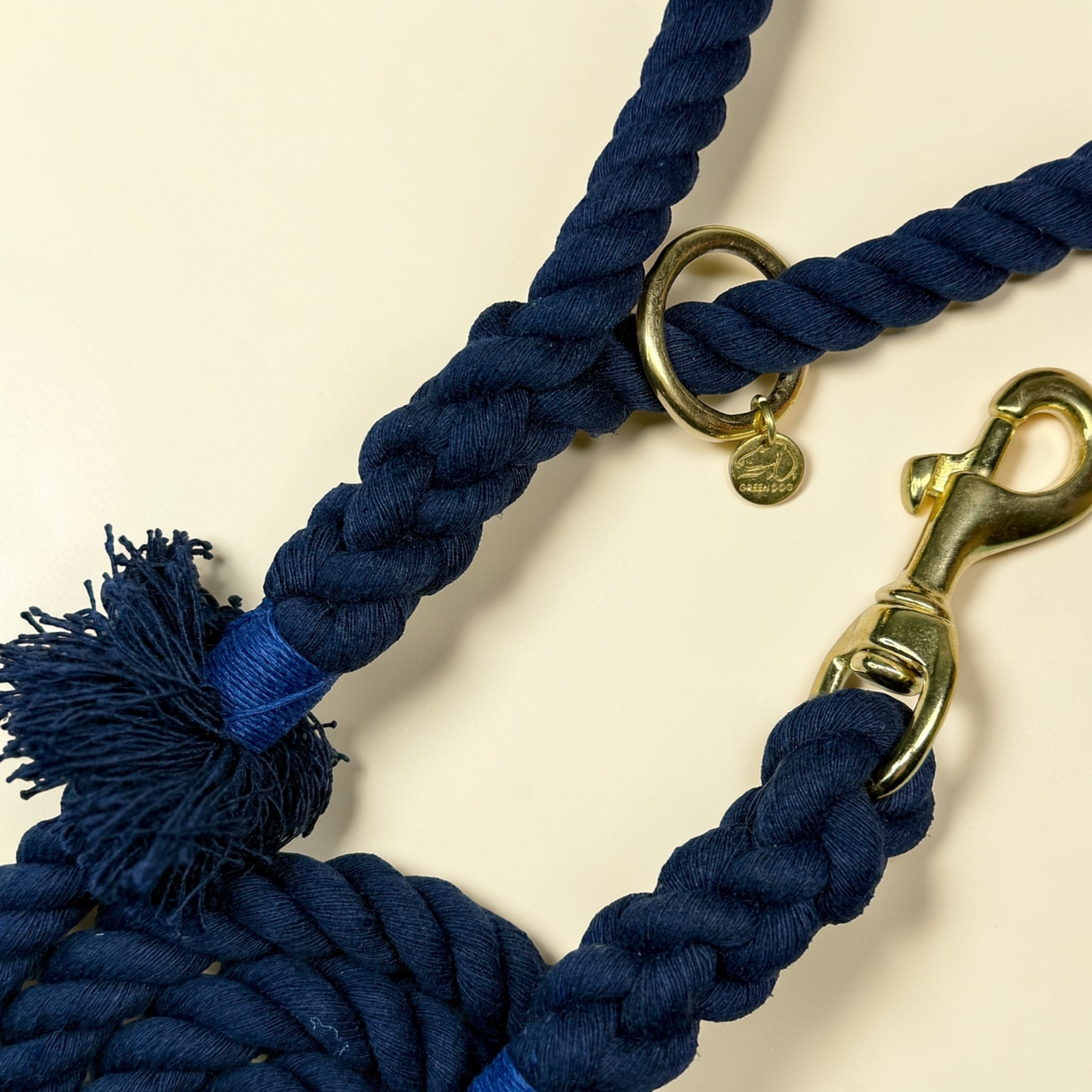 Close-up of midnight blue cotton rope dog lead showing the frayed tassel at the handle, cobalt blue binding, brass O-ring and solid brass trigger snap clip